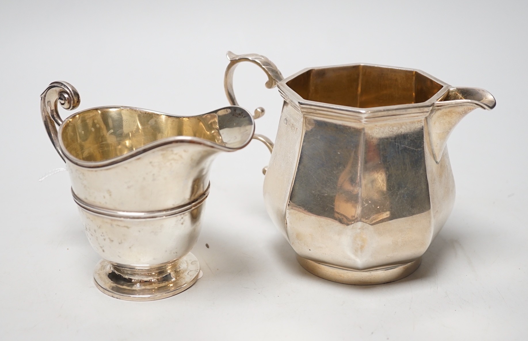 A George V panelled silver cream jug, by Elkington & Co, Birmingham, 1926, height 10cm and a late Victorian silver cream jug, London, 1899, 12.6oz.